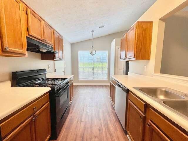 kitchen with lofted ceiling, hanging light fixtures, black range with gas cooktop, dishwasher, and light wood-type flooring