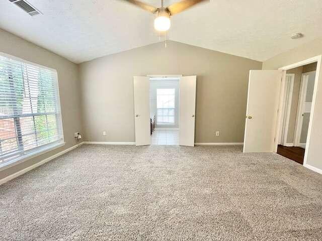 spare room featuring carpet floors, a healthy amount of sunlight, lofted ceiling, and ceiling fan