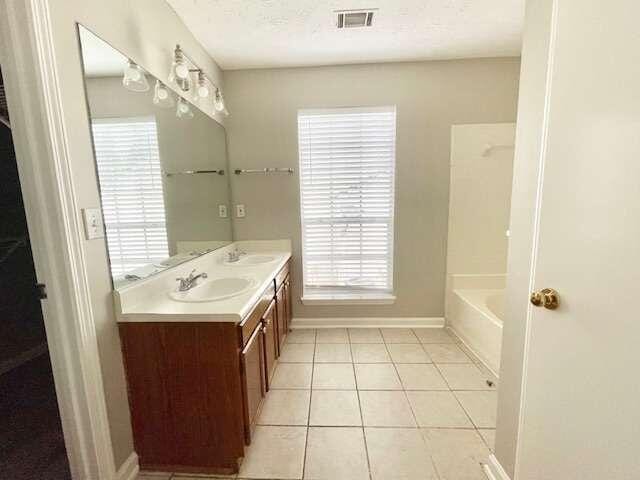 bathroom with a tub to relax in, tile patterned flooring, and vanity