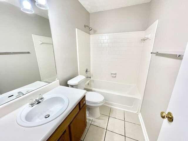 full bathroom with tub / shower combination, tile patterned floors, vanity, and toilet