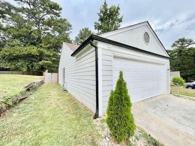 view of side of property featuring a garage and a lawn