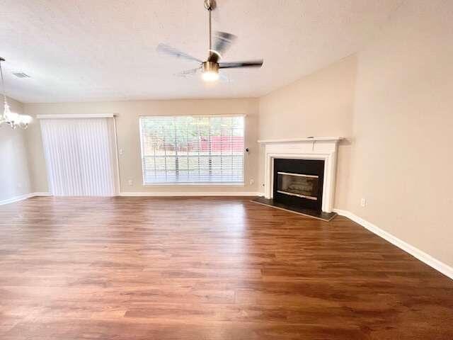 unfurnished living room featuring wood-type flooring and ceiling fan with notable chandelier