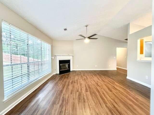 unfurnished living room featuring ceiling fan, lofted ceiling, and hardwood / wood-style floors