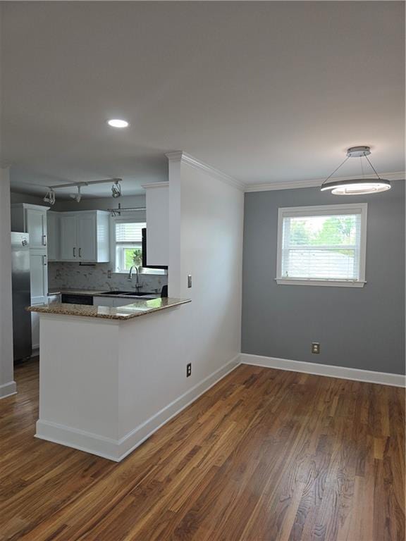 48 Peachtree Ave NE Unit 321, Atlanta, GA 30305 - kitchen featuring crown molding, dark wood finished floors, a peninsula, tasteful backsplash, and white cabinetry