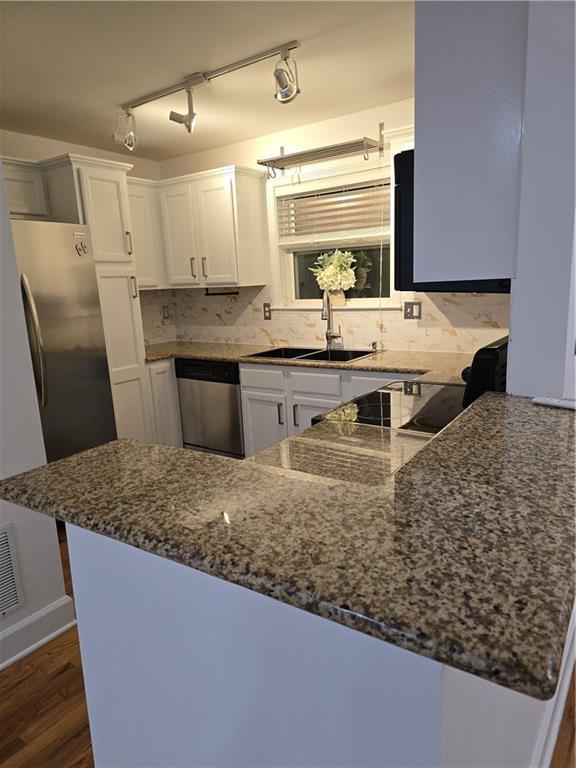 48 Peachtree Ave NE Unit 321, Atlanta, GA 30305 - kitchen with stainless steel dishwasher, white cabinetry, dark stone countertops, tasteful backsplash, and dark wood finished floors