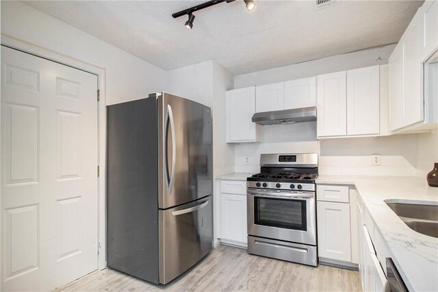 1025 Lakeside Cir, Covington, GA 30016 - kitchen with white cabinets, appliances with stainless steel finishes, under cabinet range hood, and light wood finished floors