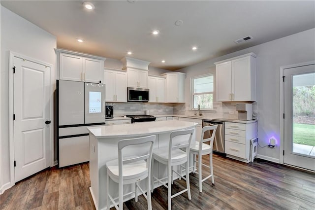 5215 Wheeler Run Dr, Auburn, GA 30011 - kitchen featuring stainless steel appliances, a center island, light countertops, backsplash, and dark wood-style floors