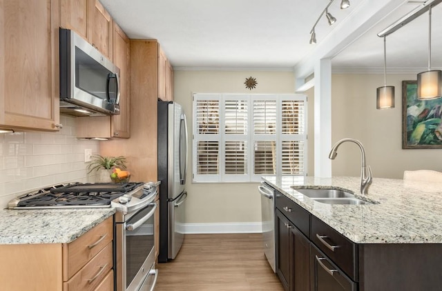 kitchen featuring sink, appliances with stainless steel finishes, ornamental molding, light stone countertops, and decorative light fixtures