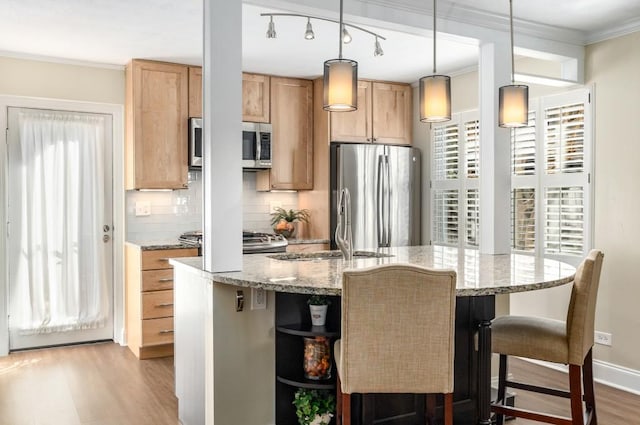 kitchen featuring a breakfast bar area, hanging light fixtures, stainless steel appliances, light stone countertops, and light wood-type flooring