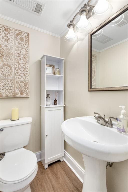 bathroom featuring ornamental molding, toilet, and hardwood / wood-style floors