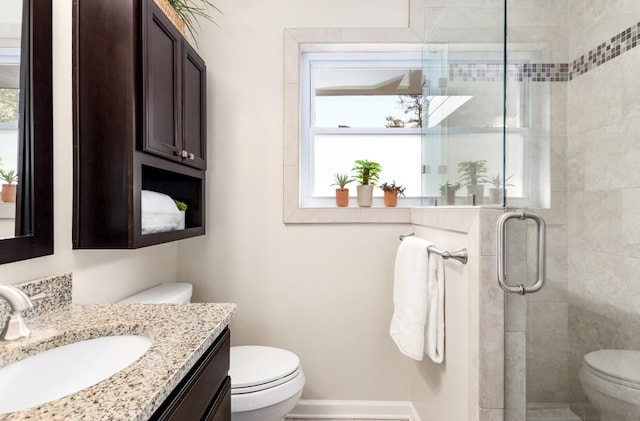 bathroom featuring vanity, a shower with door, and toilet