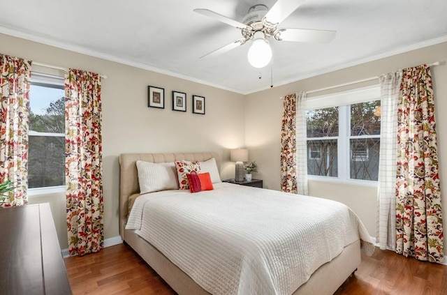 bedroom featuring crown molding, ceiling fan, hardwood / wood-style floors, and multiple windows