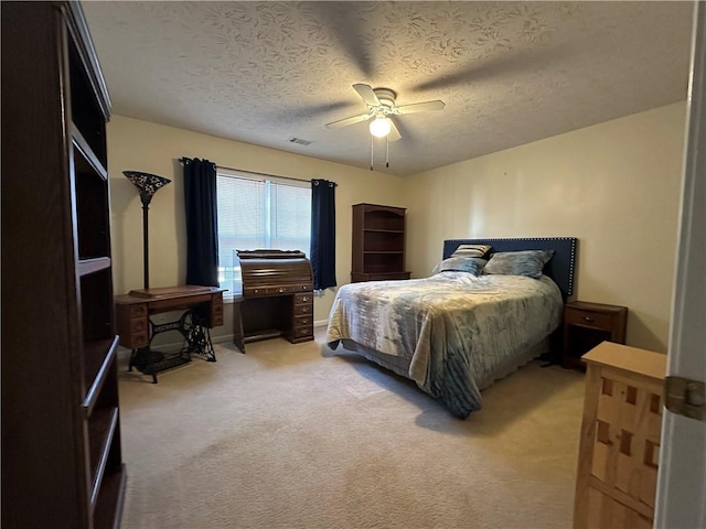 bedroom with ceiling fan, a textured ceiling, and light carpet