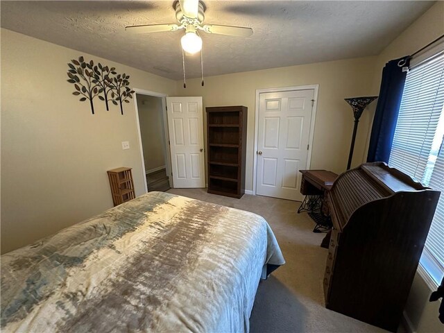 carpeted bedroom featuring a textured ceiling, multiple windows, and ceiling fan