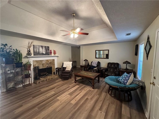 living room featuring hardwood / wood-style flooring, ceiling fan, and a raised ceiling