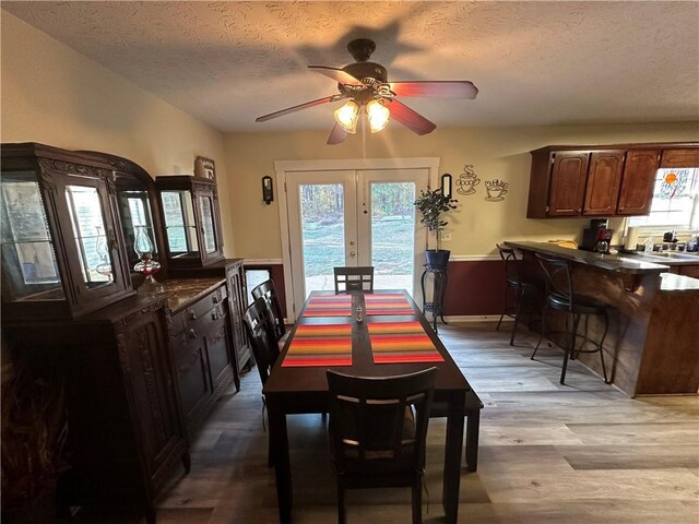 dining space with ceiling fan, french doors, a textured ceiling, and light wood-type flooring