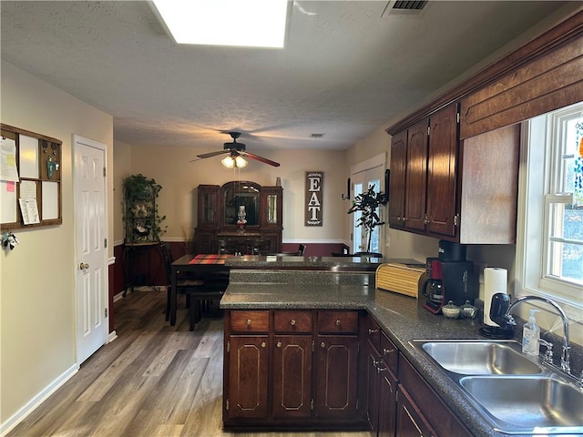 kitchen with a textured ceiling, sink, dark brown cabinets, and light wood-type flooring