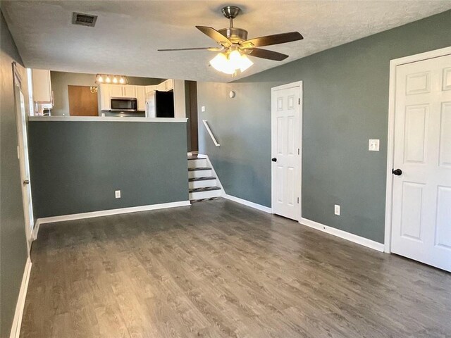 unfurnished living room with dark wood finished floors, baseboards, visible vents, and a ceiling fan