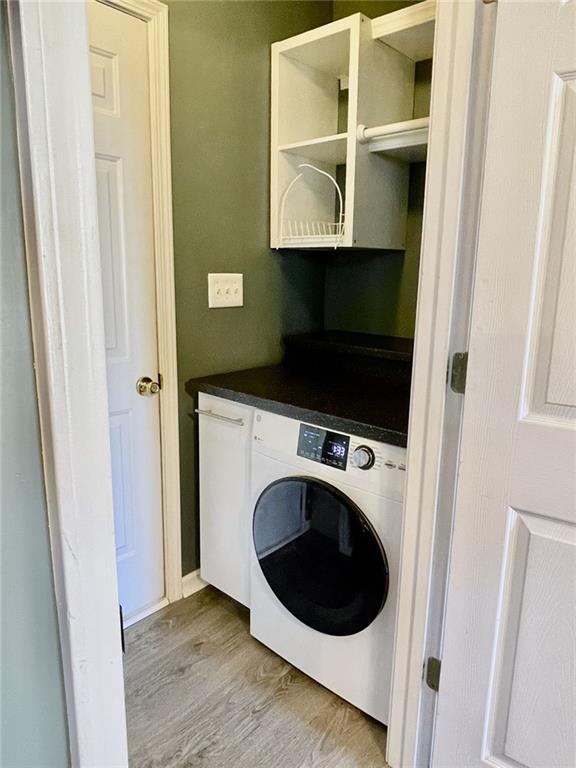 clothes washing area featuring washer / clothes dryer and light wood-type flooring