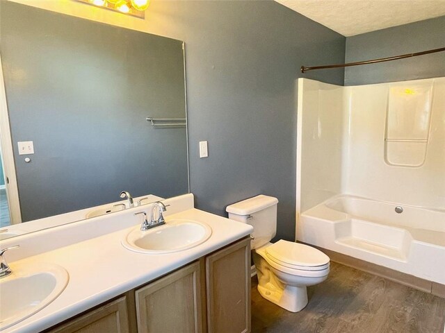 full bath featuring double vanity, wood finished floors, toilet, and a sink