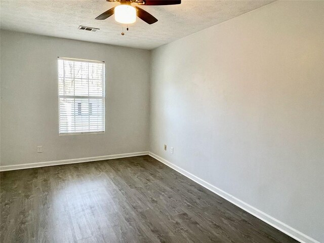 empty room featuring visible vents, ceiling fan, baseboards, dark wood-style floors, and a textured ceiling