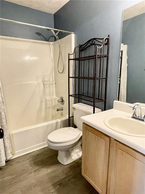 full bathroom with vanity, wood finished floors, shower / bath combo with shower curtain, a textured ceiling, and toilet