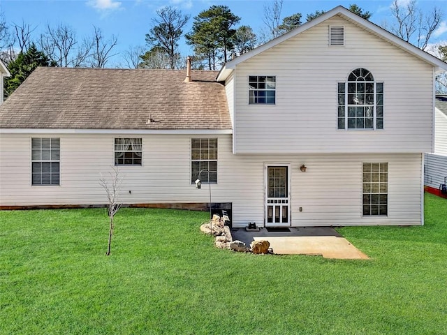 rear view of house featuring a patio, a shingled roof, and a yard