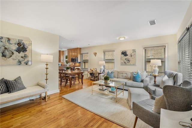 living area with light wood finished floors, visible vents, recessed lighting, and baseboards