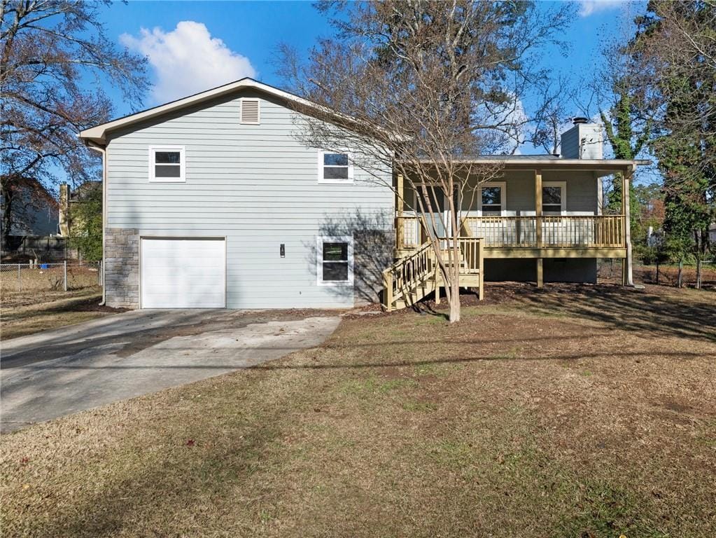 back of property featuring a garage, a yard, and covered porch