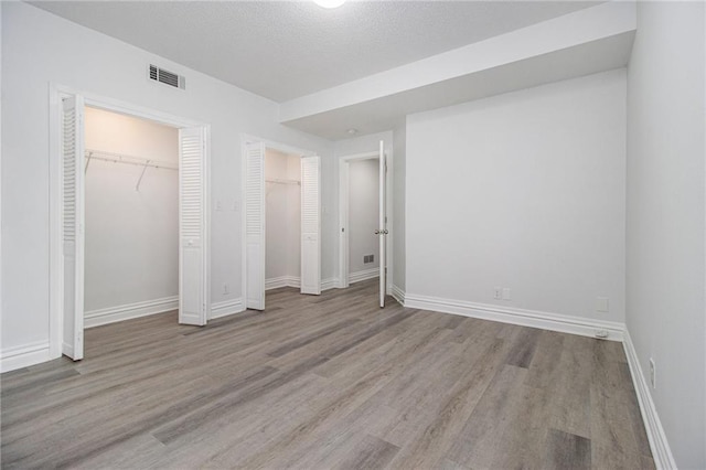 5690 Rutland Trce, Lithonia, GA 30058 - unfurnished bedroom with wood finished floors, multiple closets, and a textured ceiling
