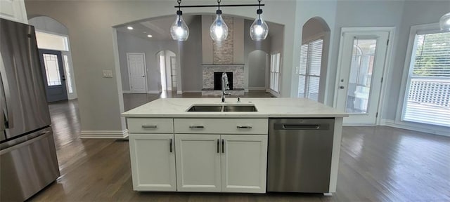 5690 Rutland Trce, Lithonia, GA 30058 - kitchen featuring stainless steel appliances, dark wood finished floors, light stone counters, hanging light fixtures, and arched walkways
