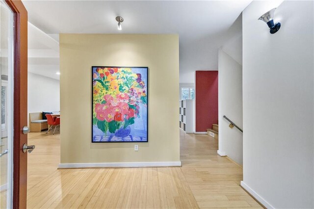 hallway featuring light wood-style floors, stairway, and baseboards