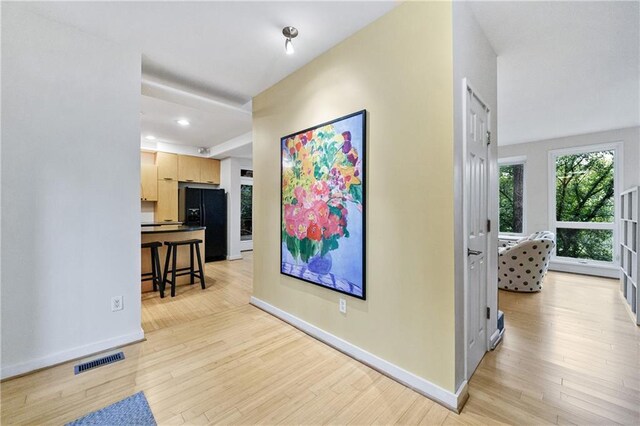 corridor featuring light wood finished floors, recessed lighting, visible vents, and baseboards