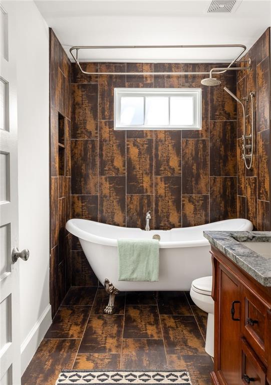 bathroom featuring a freestanding tub, toilet, vanity, and a tile shower