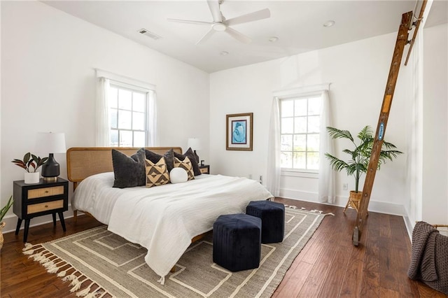 bedroom with ceiling fan, visible vents, baseboards, and hardwood / wood-style floors