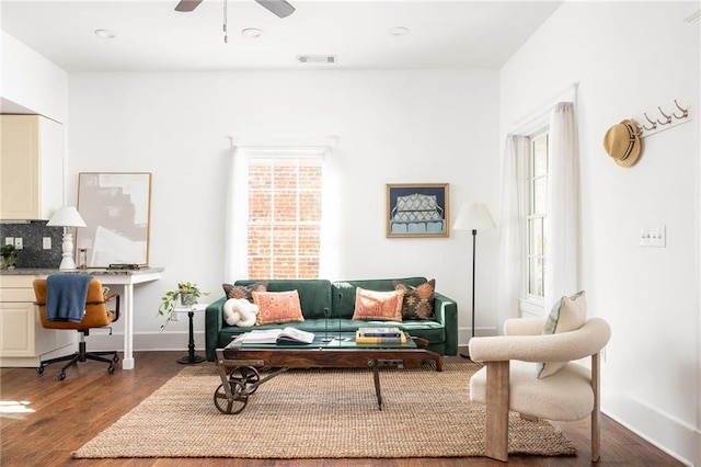 living area with visible vents, ceiling fan, baseboards, and wood finished floors