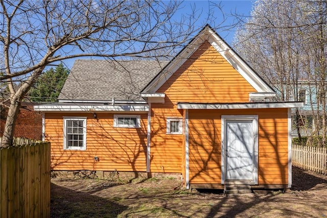 back of house with roof with shingles and fence