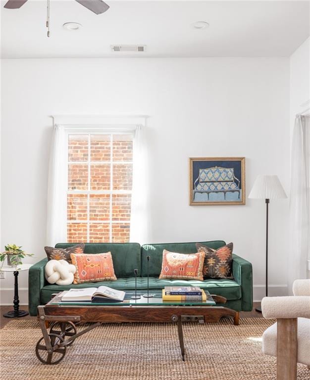 living room featuring visible vents, baseboards, and a ceiling fan