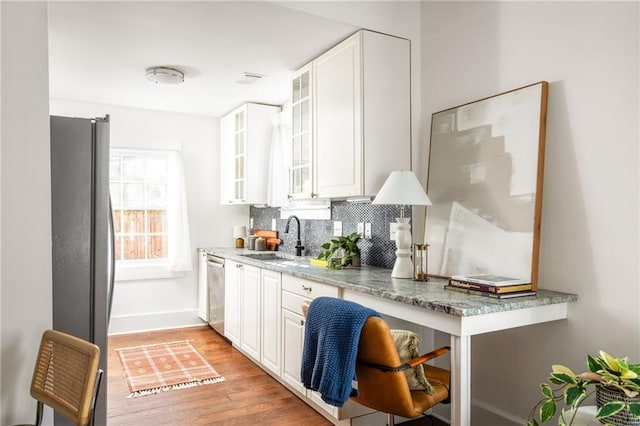 kitchen featuring a sink, backsplash, stainless steel appliances, white cabinets, and light wood finished floors