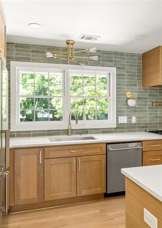 762 Rockbridge Rd NW, Lilburn, GA 30047 - kitchen featuring dishwasher, a sink, light countertops, light wood-type flooring, and decorative backsplash