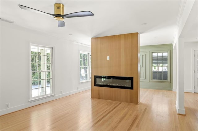 762 Rockbridge Rd NW, Lilburn, GA 30047 - unfurnished living room with light wood-style floors, ornamental molding, plenty of natural light, a glass covered fireplace, and ceiling fan