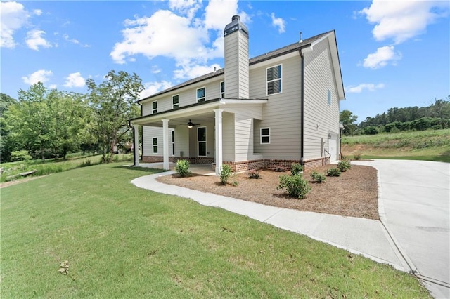 back of property with ceiling fan, covered porch, and a lawn