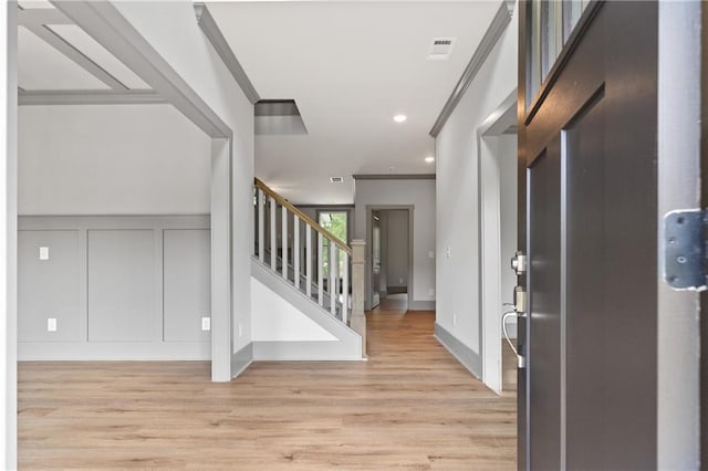 entrance foyer featuring ornamental molding and light hardwood / wood-style floors