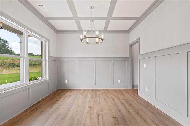 unfurnished dining area featuring beamed ceiling, coffered ceiling, a chandelier, and light hardwood / wood-style floors