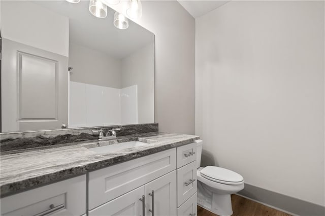 bathroom with vanity, hardwood / wood-style floors, walk in shower, and toilet