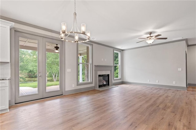 unfurnished living room with ceiling fan with notable chandelier, ornamental molding, and light hardwood / wood-style floors