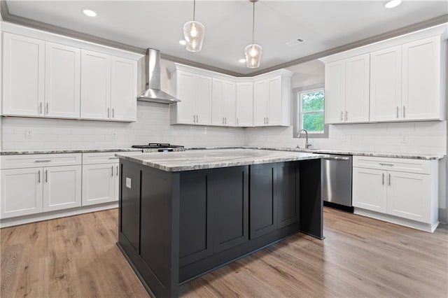 kitchen featuring white cabinets, decorative light fixtures, dishwasher, and wall chimney range hood