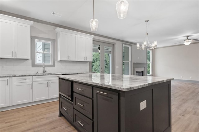 kitchen featuring white cabinetry, sink, pendant lighting, and black microwave