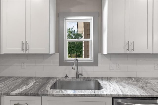 kitchen featuring tasteful backsplash, light stone countertops, sink, and white cabinets