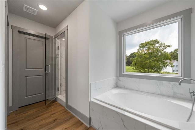 bathroom with independent shower and bath and wood-type flooring